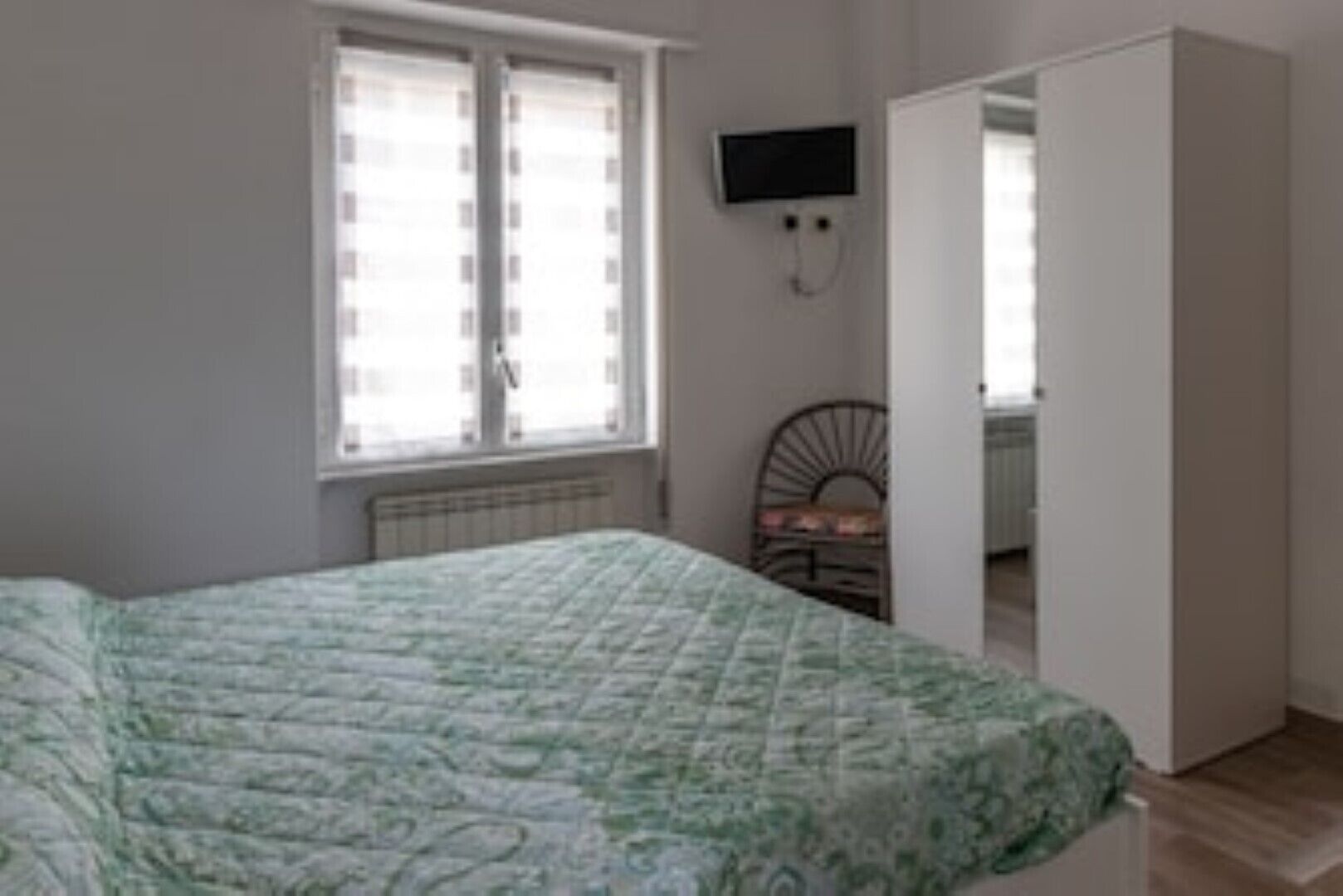 Una camera da letto con un letto, un termosifone, una TV a muro e un armadio.