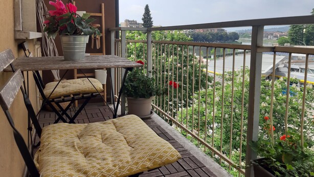 Een balkon met een houten tafel, stoelen en plantenpotten.