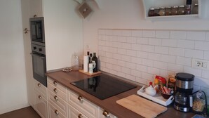 Een keuken met een inbouwoven, een magnetron, een houten aanrechtblad en een koffiezetapparaat.