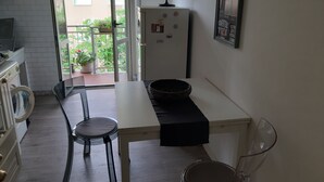 Een compacte keuken met een eethoek, een koelkast, een wasmachine en een kamerplant.