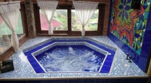 Ein Whirlpool mit blau gefliestem Boden und Wand aus Mosaik.