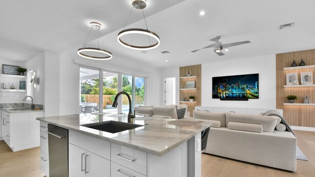 A modern kitchen with a central island, a dining area with a sofa, and a living room with a TV. - 18 Managed By Brampton Park (Delray Beach)