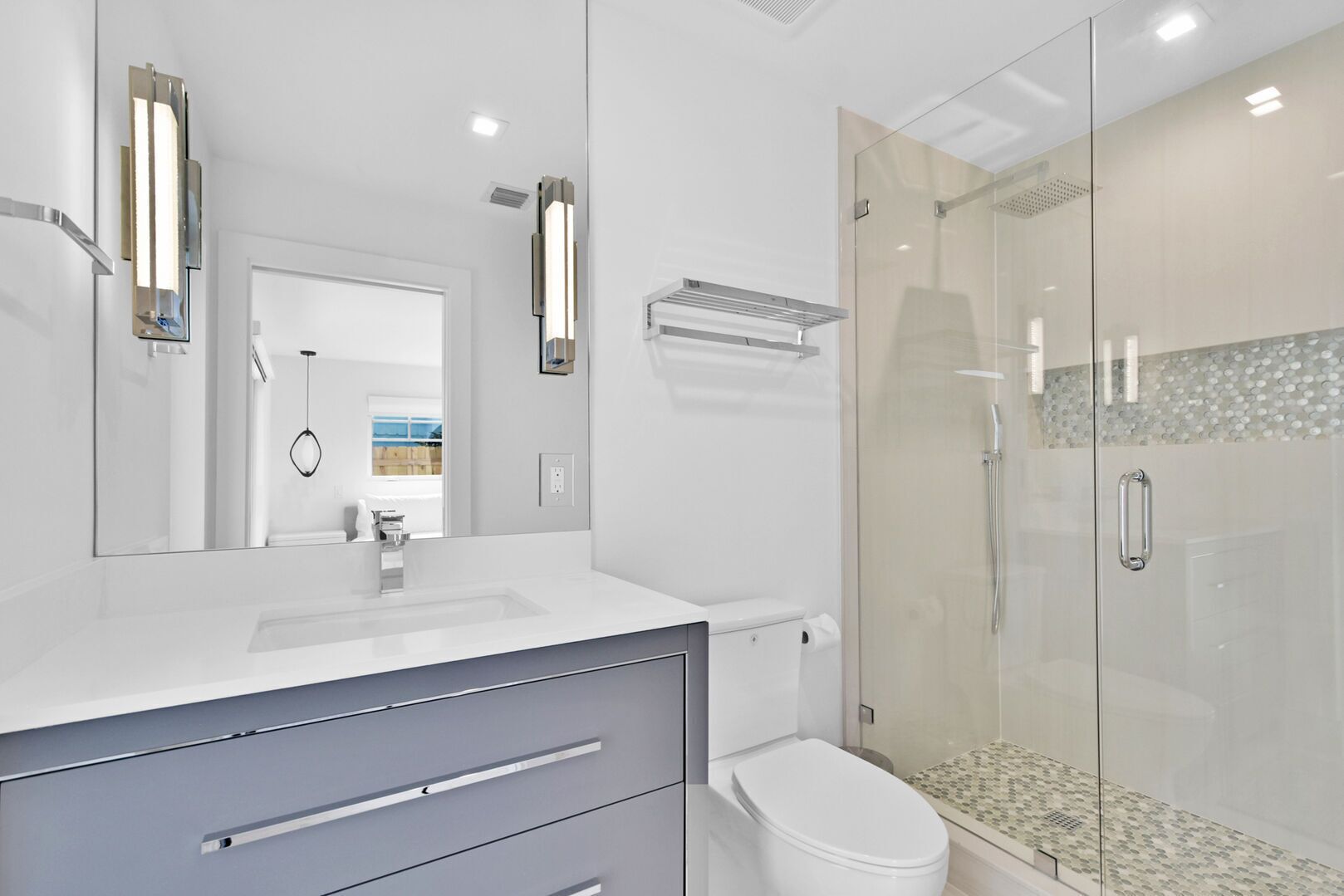 A modern bathroom with a glass shower enclosure, a white sink, and a toilet.