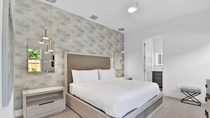 A modern bedroom with a large bed, bedside tables, a wardrobe, and a mirror. - 18 Managed By Brampton Park (Delray Beach)