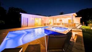 Une maison moderne dotée d’une piscine et d’un espace extérieur aménagé pour se détendre.