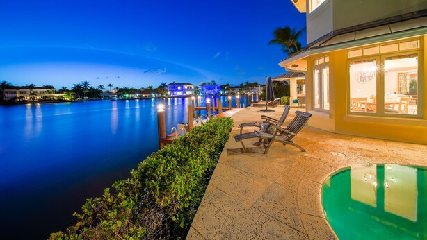 A waterfront property with a pool, outdoor seating, and a view of the water.