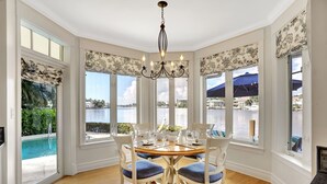 A dining area with a view of the water, a chandelier, and a pool.