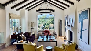 A spacious living room with a high ceiling, a large window, and a fireplace. - Montecito - Ocean and Mountain Views - Total Renovation Completed! (Montecito)