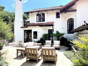A two-story house with a patio area featuring outdoor furniture, including sofas and chairs. - Montecito - Ocean and Mountain Views - Total Renovation Completed! (Montecito)