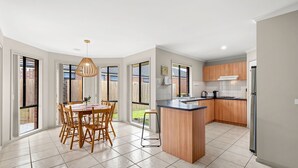 A modern kitchen with wooden cabinets, a central island, and a dining area with a table and chairs.
