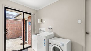 A laundry room with a washing machine and dryer, a water heater, and a door leading to a brick exterior.