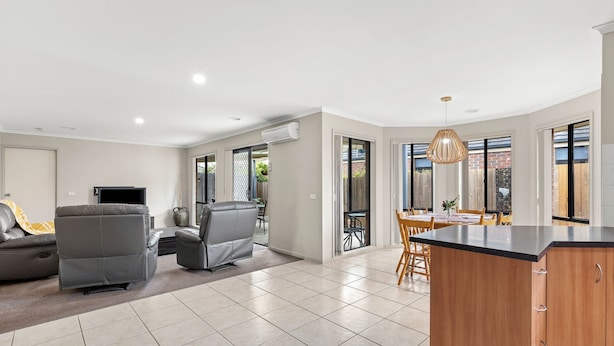 A modern living room with a sofa, TV, and a dining area with a table and chairs.