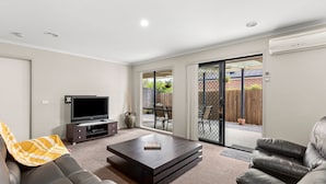 A modern living room with a flat-screen TV, a coffee table, and leather sofas.