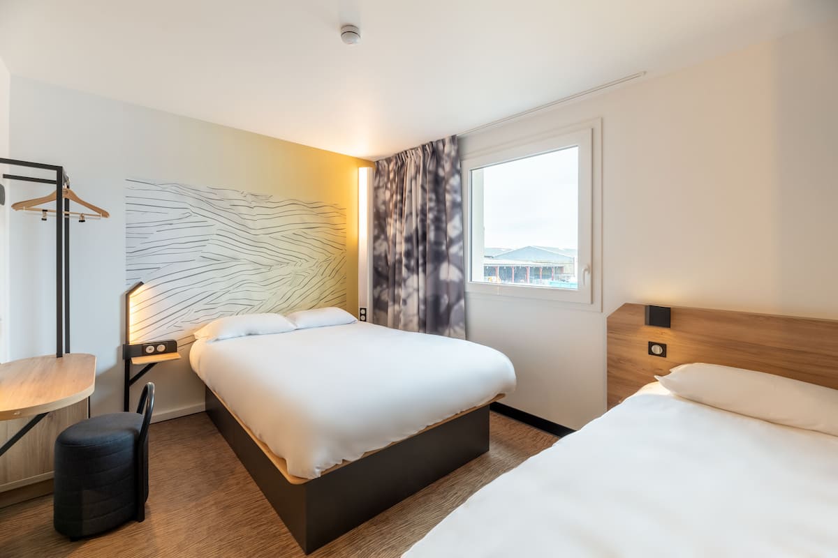 Quarto de hotel com cama grande, mesas de cabeceira, escrivaninha e uma cadeira.