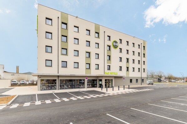 Un hotel tipo B&B con diseño moderno, varios pisos y un estacionamiento al frente.
