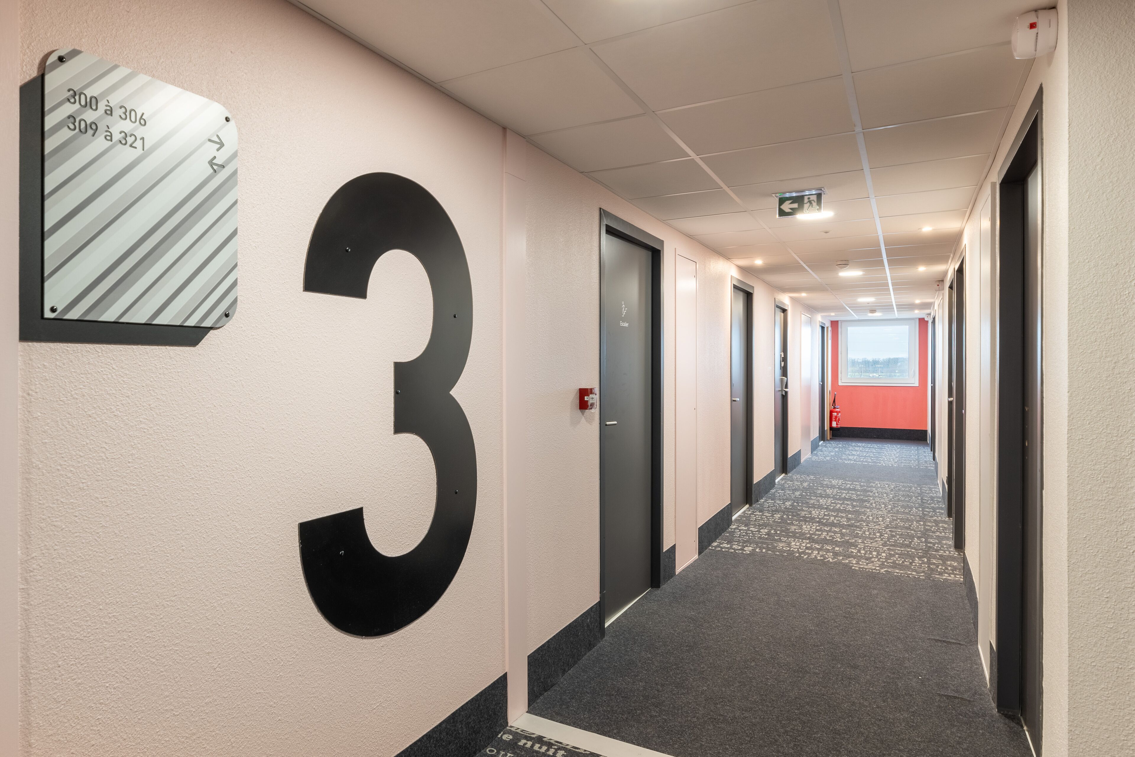 A hallway with a large number 3 sign, doors, and a carpeted floor.