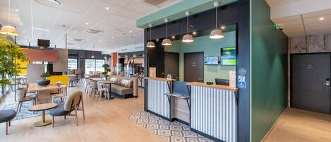 A modern reception area with a counter, seating, and a large window.