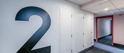 A hallway with a large number '2' on the wall, white doors, and a red-framed doorway at the end.