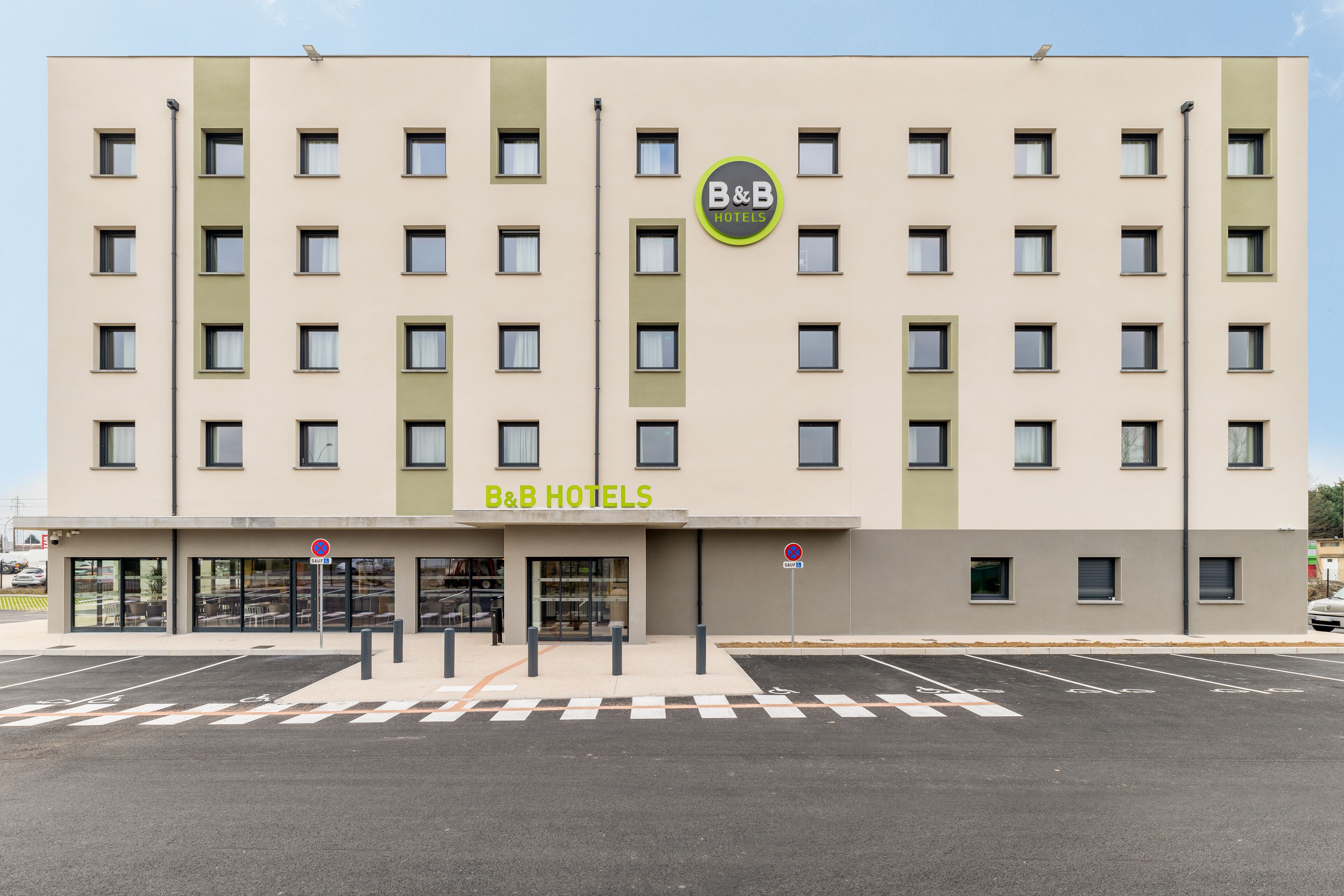 A B&B hotel with a modern facade, multiple windows, and a parking lot in front.