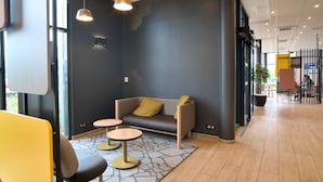A modern interior with a sofa, two small tables, and a yellow chair. - B&B HOTEL Dreux Nord (Dreux)