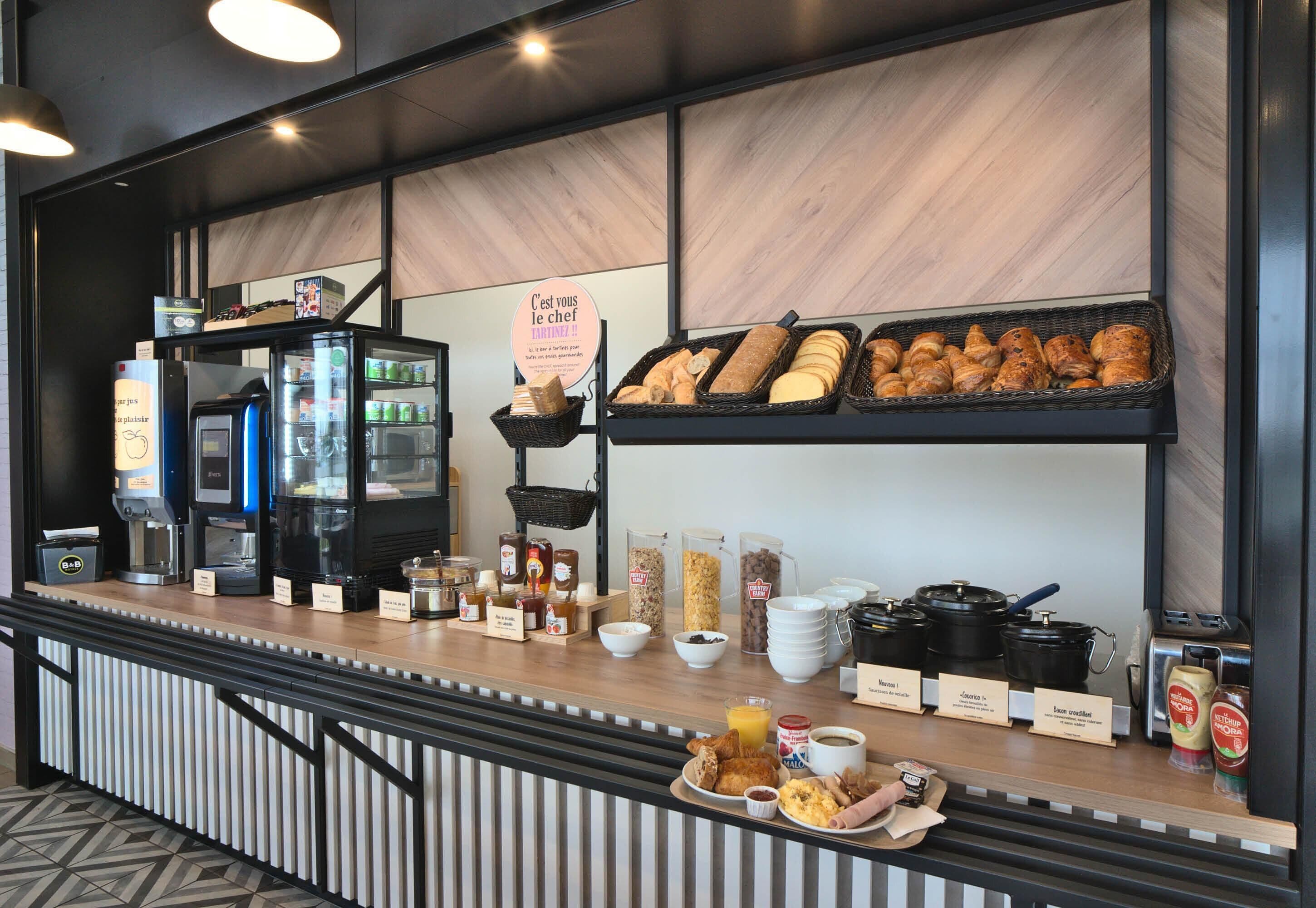 A breakfast buffet with various food items, a coffee machine, and a sign indicating the chef.
