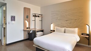 A hotel room with a large bed, bedside tables, a mirror, a coat rack, and a wall art piece. - B&B HOTEL Dreux Nord (Dreux)