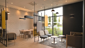 A modern interior with a dining area, seating, and large windows. - B&B HOTEL Dreux Nord (Dreux)