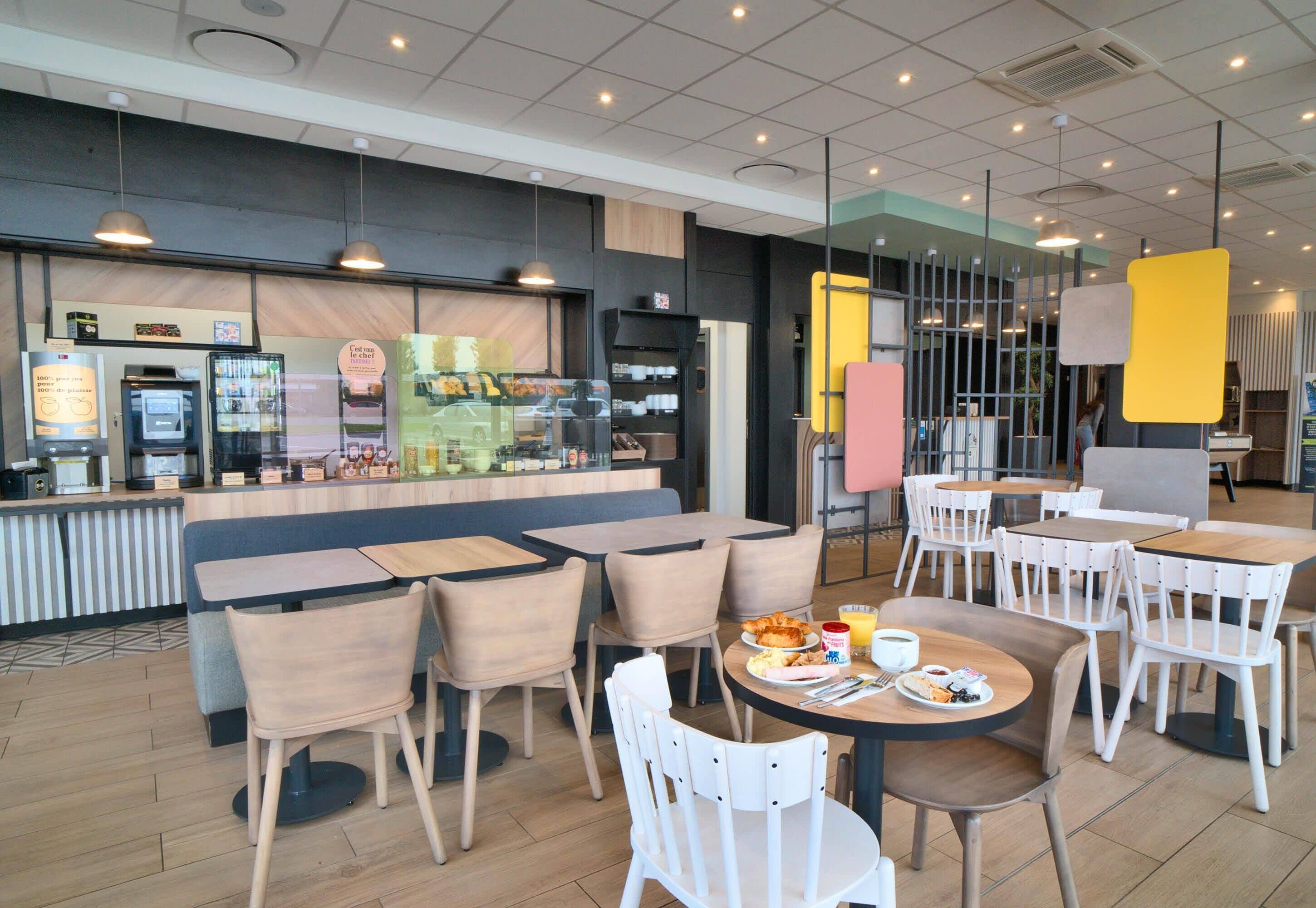Een modern café met zitmogelijkheden, een toonbank met drankjes en een zichtbaar menu.