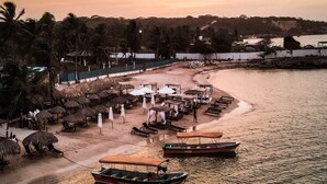 A beach with thatched umbrellas and lounge chairs, boats, and a sandy shore. -  PB-C1 Habitacion tipo Cabaña Segundo Piso (Cartagena)