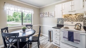 A kitchen with white cabinets, a stove, and a window with a view of greenery. - Condo Suite(15) | 4 Bed 2 Bath | Sleeps 12 (Rock Hill)