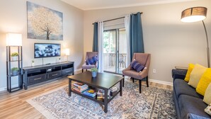 A living room with a sofa, chairs, a coffee table, a TV, and a bookshelf. - Condo Suite(15) | 4 Bed 2 Bath | Sleeps 12 (Rock Hill)