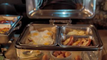 A buffet setup with various food items including eggs, bacon, and a casserole dish.