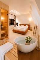 Un dormitorio moderno con una cama grande, una sauna de madera y una bañera con flores.