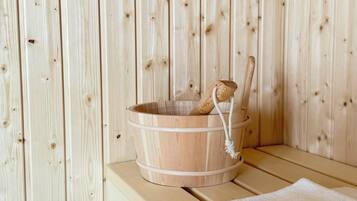 A wooden sauna with a wooden bucket and a towel on a bench.