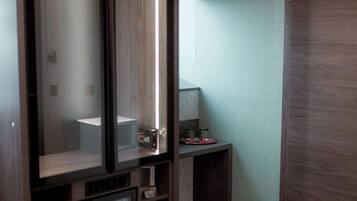 A room with a built-in entertainment unit, a small table with a lamp, and a wooden door.