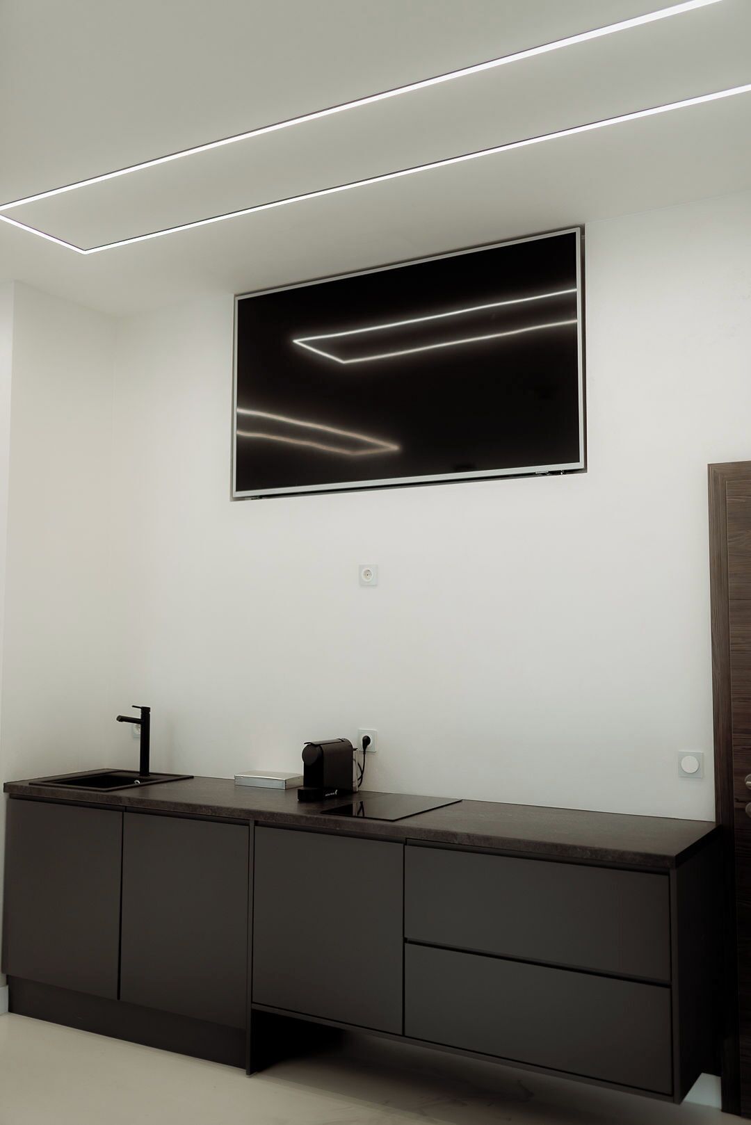 Un baño moderno con un mueble de tocador oscuro, un lavabo negro y un espejo grande.