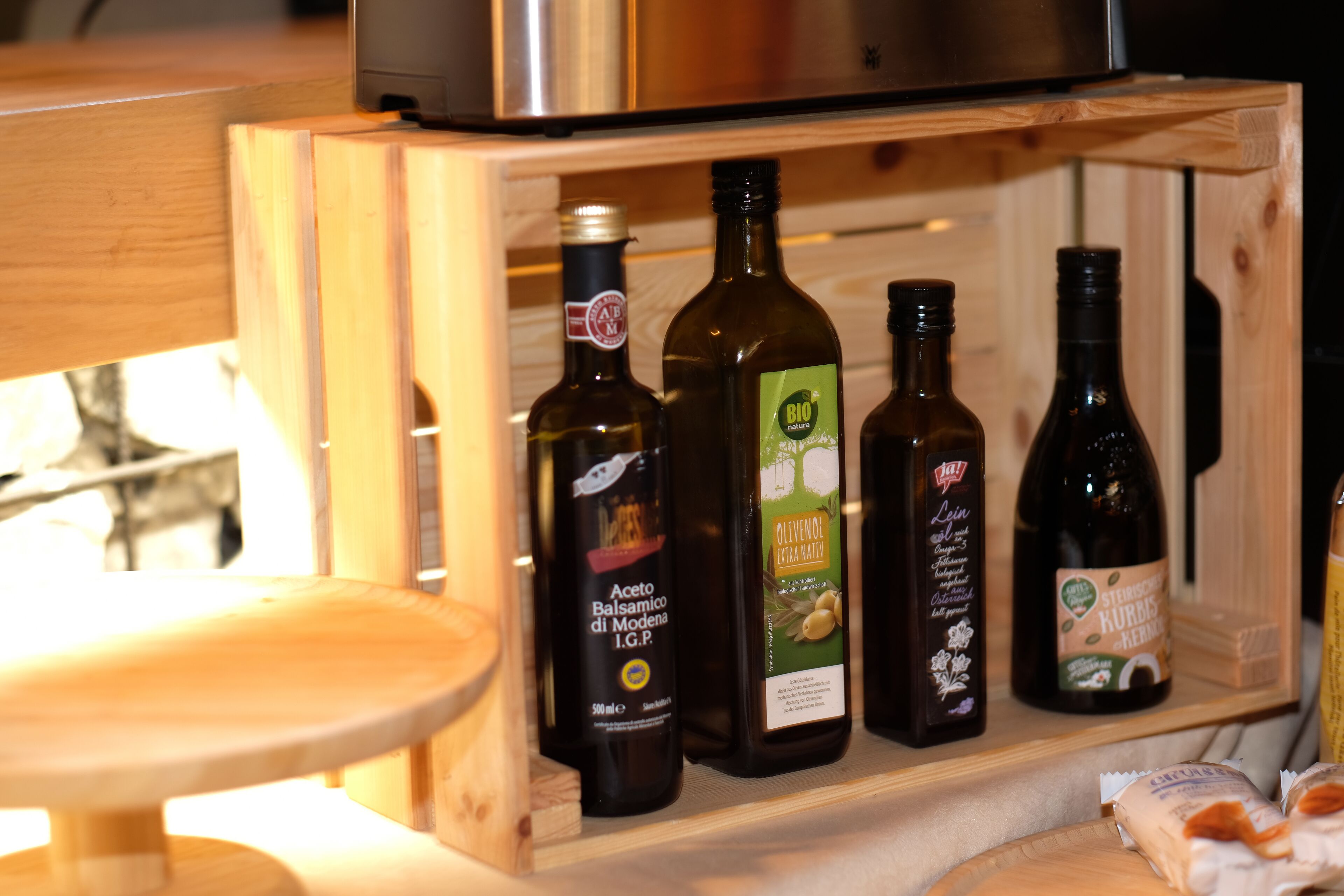 A wooden cabinet with bottles of olive oil and other condiments.