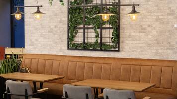 A restaurant interior with a brick wall, green vines, and hanging pendant lights.