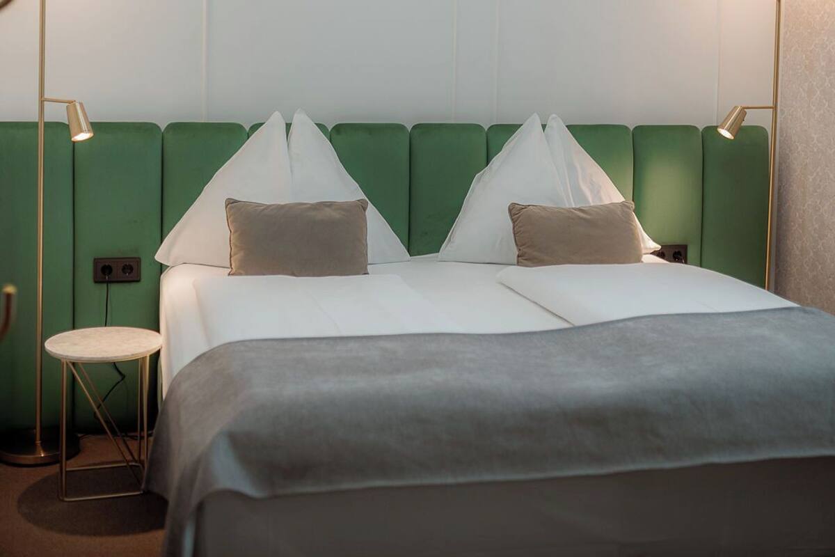 Una habitación de hotel con una cama grande, dos lámparas de noche y una pared de acento verde.