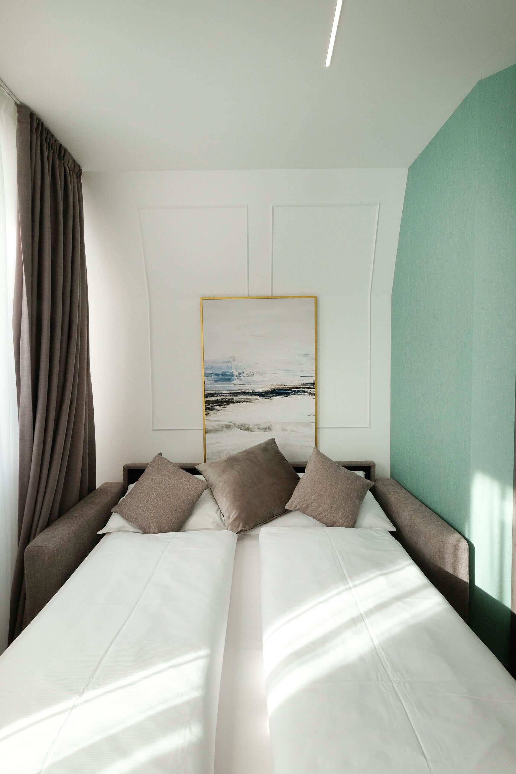 A modern hotel room with a large bed, a headboard, and a framed artwork on the wall.