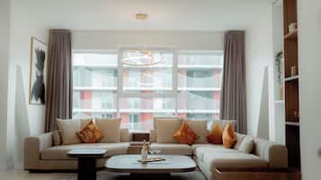 A modern living room with a beige sofa, a coffee table, and a large window with a view of a building.
