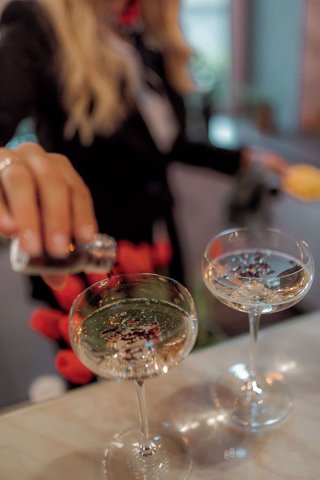 Two glasses of a clear liquid, possibly a beverage, on a reflective surface.