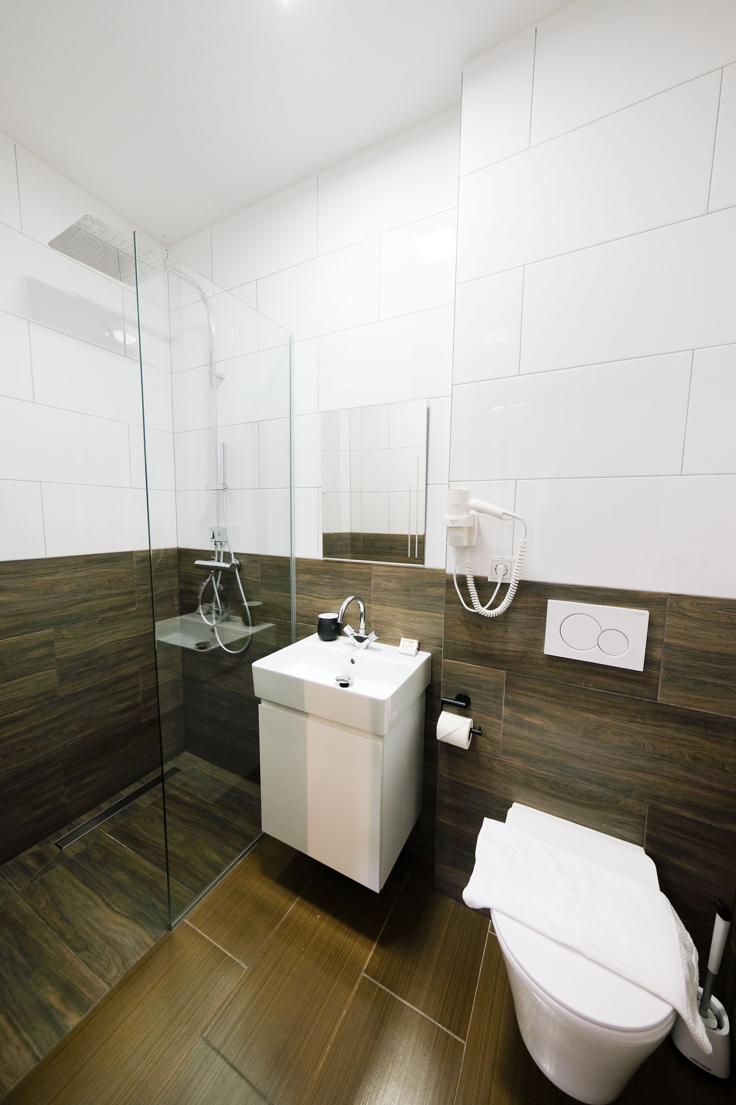 Une salle de bain moderne avec une douche à parois de verre, un lavabo blanc et des toilettes.