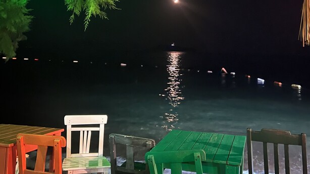 A nighttime view of a waterfront restaurant with outdoor seating and a view of the water. - Ayci Otel (Bodrum)