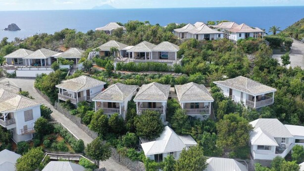 A coastal residential area with multiple houses, some with balconies, surrounded by greenery and overlooking the sea. - Impeccable 1-bed Cottage (St. Barthelemy)