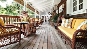 A covered outdoor area with wicker furniture and wooden flooring. - Impeccable 1-bed Cottage (St. Barthelemy)