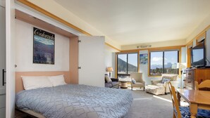 Una habitación de hotel con una cama grande, una mesa de comedor, una silla, un sofá y un televisor.