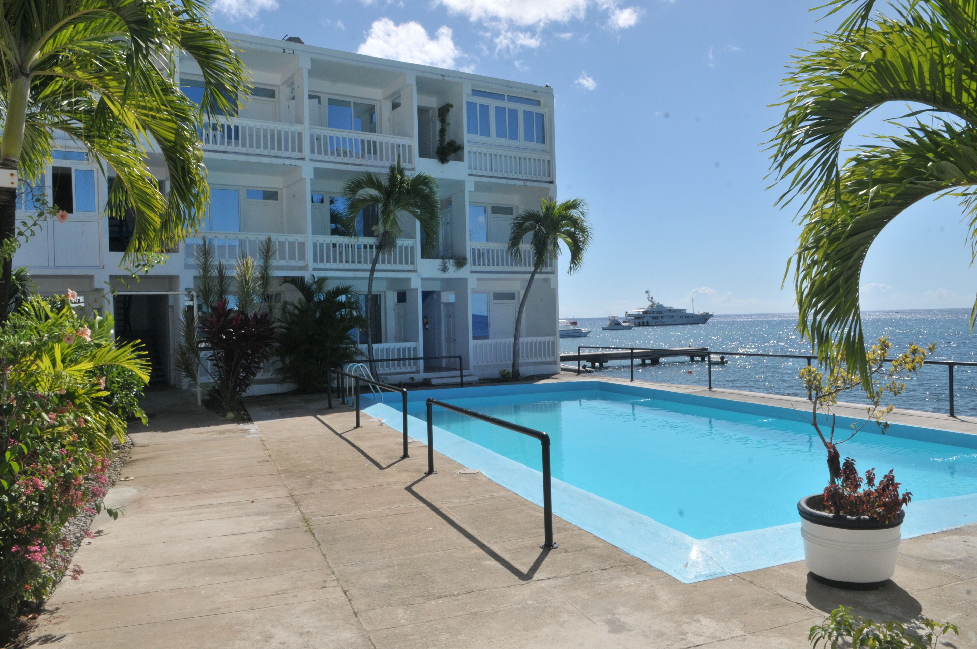 A pool area with a view of the ocean and a cruise ship in the distance.