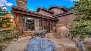 A stone patio with outdoor furniture, a covered grill, and a stone chimney. - Happy Place | Private Hot Tub • 3 King Suites • Minutes to Breck Ski Resort (Breckenridge)