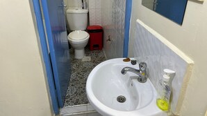 Ein kleines Badezimmer mit einem weißen Waschbecken, einem Spiegel und einer Toilette.